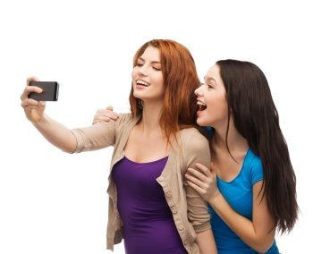 technology, friendship and people concept - two smiling teenagers taking picture with smartphone camera