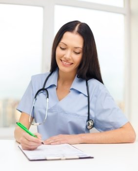 medicine and health concept - female doctor or nurse writing prescription