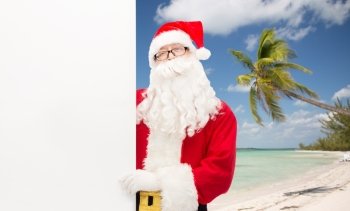 christmas, holidays, advertisement, travel and people concept - man in costume of santa claus with white blank billboard over tropical beach background