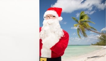 christmas, holidays, advertisement, travel and people concept - man in costume of santa claus with white blank billboard making hust gesture over tropical beach background