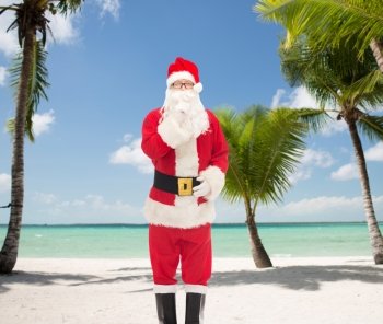 christmas, holidays and people concept - man in costume of santa claus making hush gesture over tropical beach background