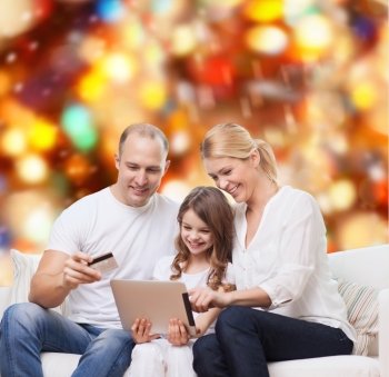 family, holidays, shopping, technology and people - smiling family with tablet pc computer and credit card over red lights background