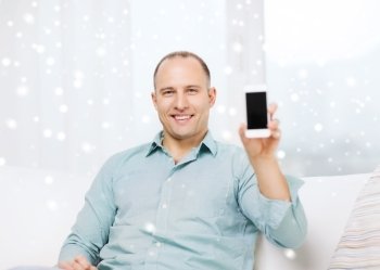 people, communication, home and technology concept - smiling man showing blank smartphone screen at home