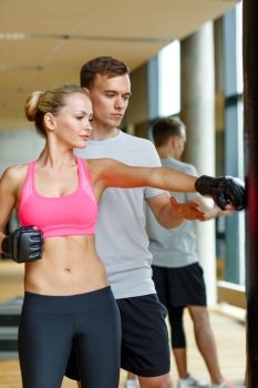 sport, fitness, lifestyle and people concept - smiling woman with personal trainer boxing in gym