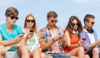 friendship, summer, technology and people concept - group of friends with smartphones and headphones outdoors