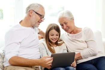 family, generation, technology and people concept - smiling grandfather, granddaughter and grandmother with tablet pc computer sitting on couch at home