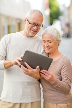 age, tourism, travel, technology and people concept - senior couple with tablet pc computer on street
