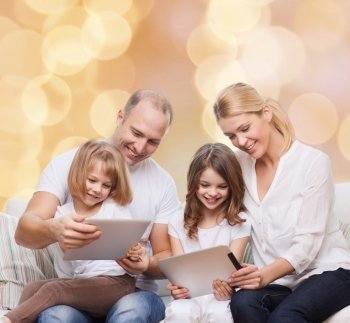family, holidays, technology and people - smiling mother, father and little girls with tablet pc computers over beige lights background