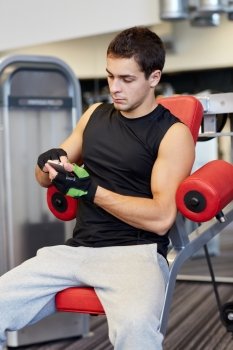 sport, bodybuilding, lifestyle, technology and people concept - young man with smartphone in gym