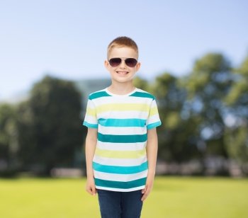 happiness, summer and people concept - smiling cute little boy in sunglasses over park background