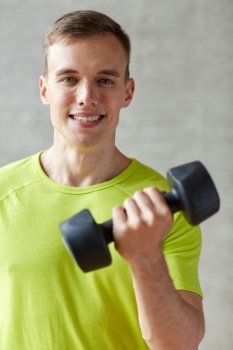 sport, fitness, lifestyle and people concept - smiling man with dumbbell flexing biceps in gym