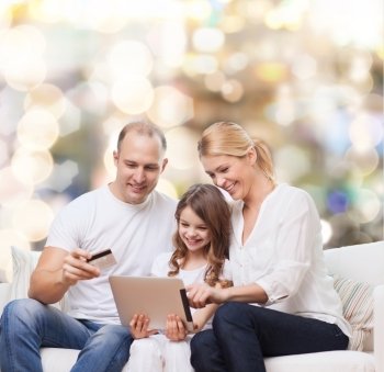 family, holidays, shopping, technology and people - smiling mother, father and little girl with tablet pc computer and credit card over lights background