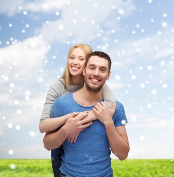 love, people and family concept - smiling couple hugging over blue sky, snow and grass background