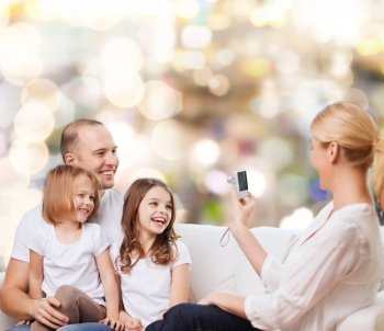 family, holidays, technology and people - smiling mother, father and little girls with camera over lights background
