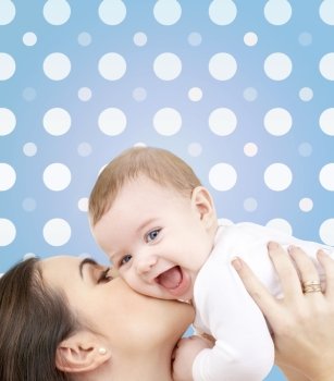 motherhood, children, adoption, happiness and people concept - happy mother kissing her baby boy over blue and white polka dots pattern background