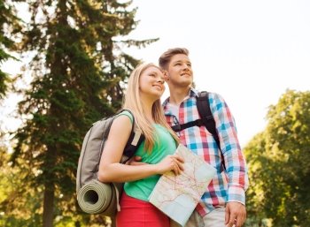 hiking, travel, vacation and friendship concept - smiling couple with map and backpack in nature
