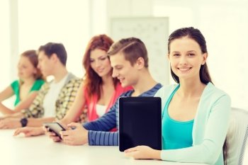 education, technology and internet concept - smiling teenage girl in front of students showing blank screen of tablet pc computer at school