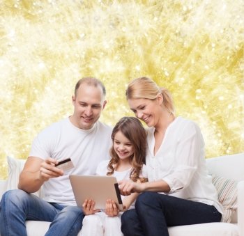 family, holidays, shopping, technology and people - smiling family with tablet pc computer and credit card over yellow lights background