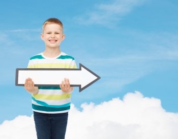 advertising, direction and childhood concept - smiling little boy with white blank arrow pointing right over blue sky