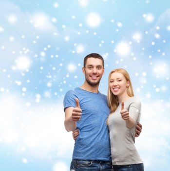 love, people and family concept - smiling couple snowing thumbs up gesture and hugging over blue sky with snow, cloud background