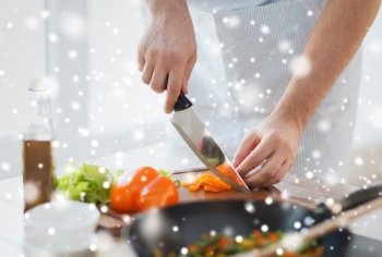 cooking, people, vegetarian food and home concept - close up of man chopping paprika and other vegetables on cutting board with big knife