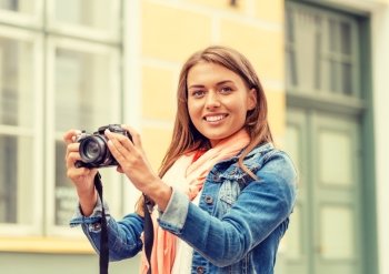 travel, vacation and technology concept - smiling girl with digital photocamera in the city