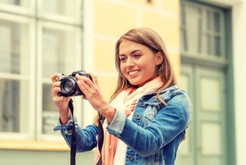 travel, vacation and technology concept - smiling girl with digital photocamera in the city