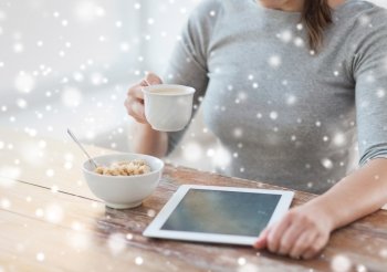 health, technology, food and home concept - close up of woman with to tablet pc computer having breakfast and drinking coffee