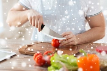 cooking, people, vegetarian food and home concept - close up of man chopping tomato and other vegetables on cutting board with big knife