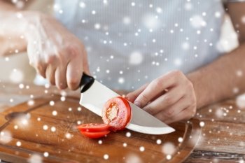 cooking, people, vegetarian food and home concept - close up of man chopping tomato and other vegetables on cutting board with big knife
