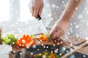 cooking, people, vegetarian food and home concept - close up of man chopping paprika and other vegetables on cutting board with big knife