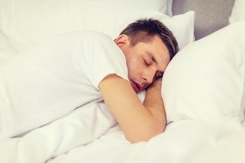 hotel, travel and happiness concept - handsome man sleeping in bed