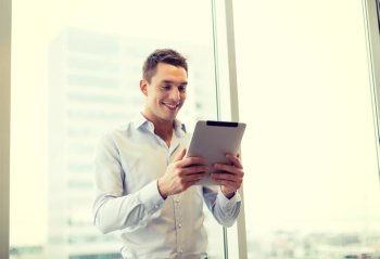 business, technology, internet and office concept - smiling businessman with tablet pc computer in office