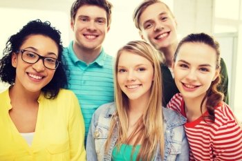 education and happiness concept - group of young smiling people at home or school