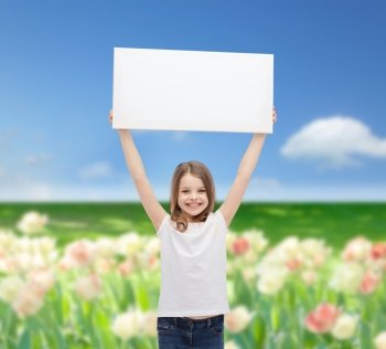 advertisement, childhood, happiness and people concept - smiling little child in white t-shirt holding blank board over blue sky and field of flowers background