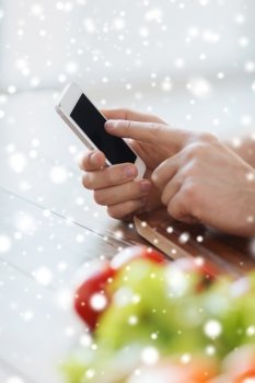 cooking, people, technology and home concept - close up of man with vegetables on table showing blank smartphone screen in kitchen
