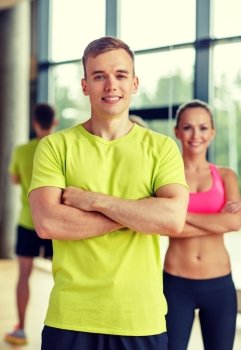 sport, fitness, lifestyle and people concept - smiling man and woman in gym