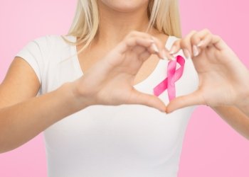 healthcare, people, charity, gesture and medicine concept - close up of young woman in blank white t-shirt with breast cancer awareness ribbon showing heart shape over pink background