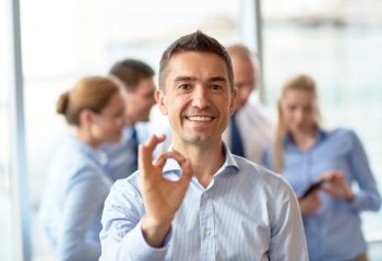 business, people and teamwork concept - smiling businessman showing ok gesture with group of businesspeople meeting in office