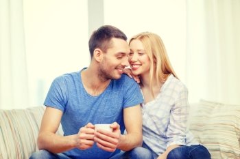 love, family, healthy food and happiness concept - smiling man with cup of tea or coffee with wife or girlfriend at home