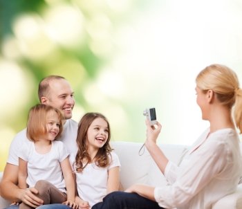 family, technology, ecology and people - smiling mother, father and little girls with camera over green background