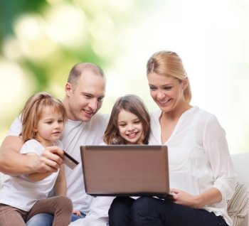 family, shopping, technology and people - happy family with laptop computer and credit card over green background