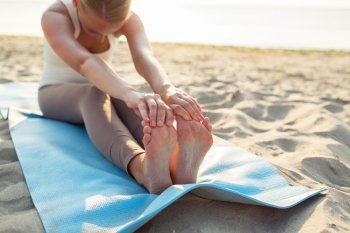 fitness, sport, people and lifestyle concept - close up of woman making yoga exercises on mat outdoors
