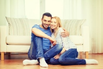 love, family and happiness concept - smiling happy couple sitting on floor at home