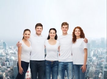 advertising, friendship, and people concept - group of smiling teenagers in white blank t-shirts over city background