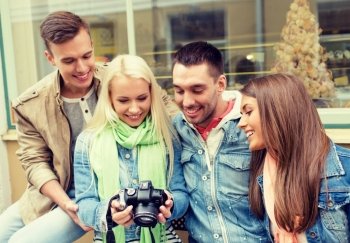 travel, vacation, technology and friendship concept - group of smiling friends with digital photocamera in the city