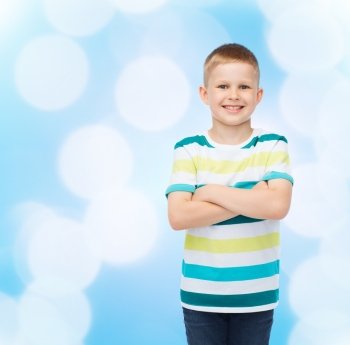 happiness, childhood and people concept - smiling little boy in casual clothes with crossed arms over blue background