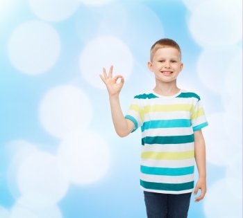 childhood, accomplishment, gesture and people concept - smiling little boy in casual clothes making OK gesture over blue background