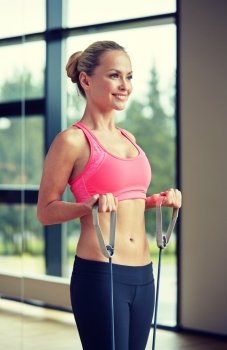 fitness, sport, people and lifestyle concept - smiling woman doing exercises with expander in gym