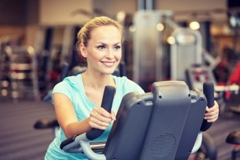 sport, fitness, lifestyle, technology and people concept - smiling woman exercising on exercise bike in gym